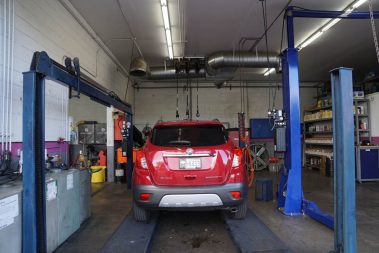 A red car getting fixed at The Muffler Shop