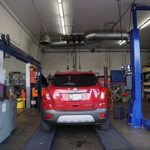 A red car getting fixed at The Muffler Shop