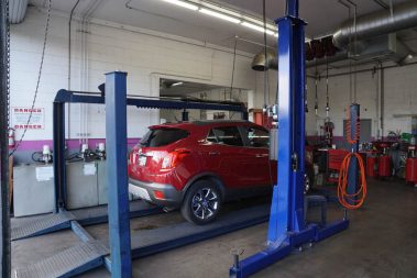 A red car getting fixed at The Muffler Shop